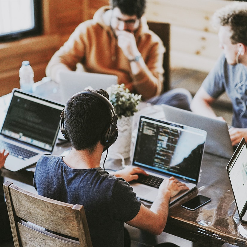 Picture of 4 people siting on a table with their laptops